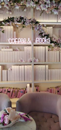 A bright, inviting reading area with modern seating, soft lighting, and a small counter serving tea and coffee.