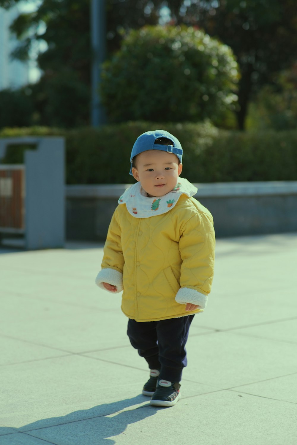 a little boy in a yellow jacket and blue hat