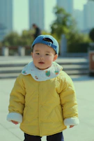 Smiling children wearing vibrant jackets and hats playing in a park.