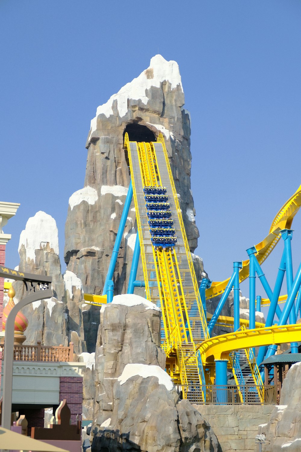 a yellow and blue roller coaster at a theme park