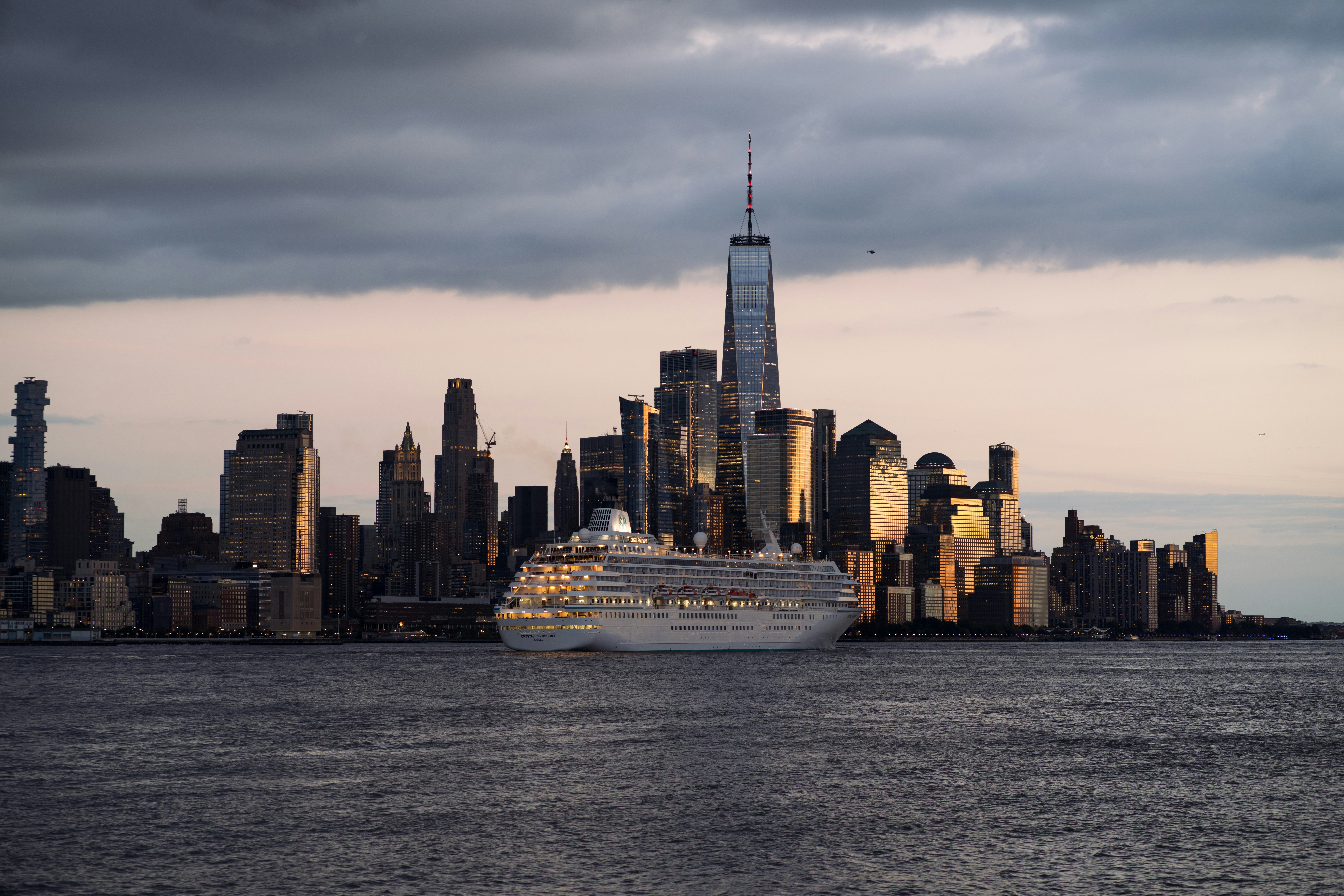 a large cruise ship in front of a city skyline, Nyc skyline sunset from NJ
