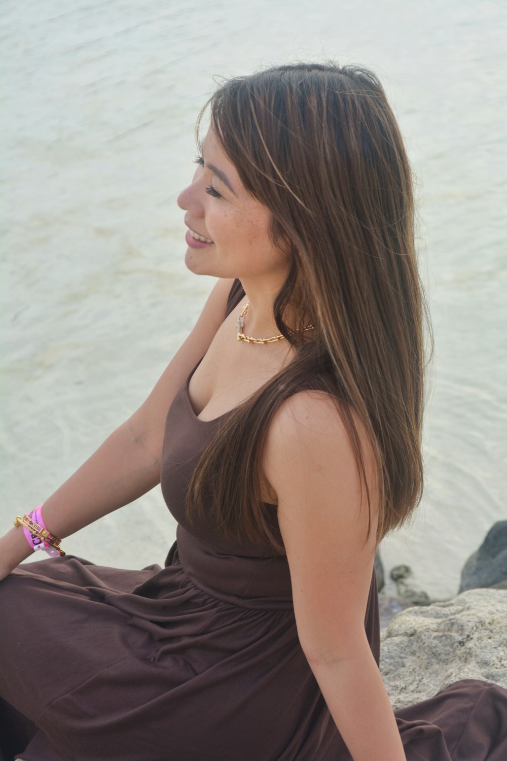 una donna seduta su una roccia vicino all'acqua