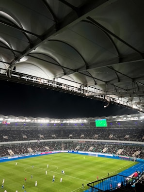 Action shot of a player catching a football mid-air, with gold and yellow stadium lights shining.