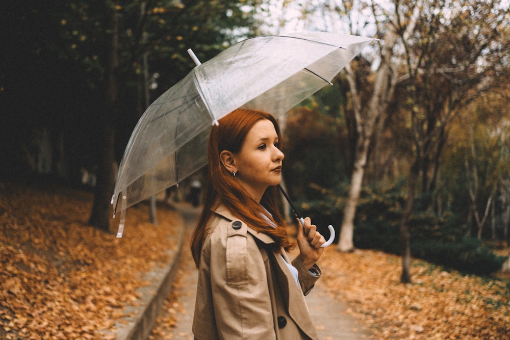 a woman holding an umbrella while standing on a path