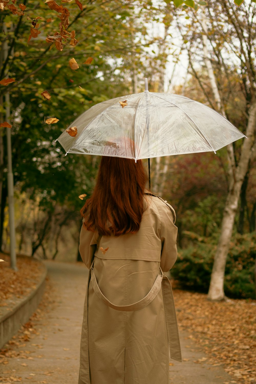 a woman walking down a path holding an umbrella