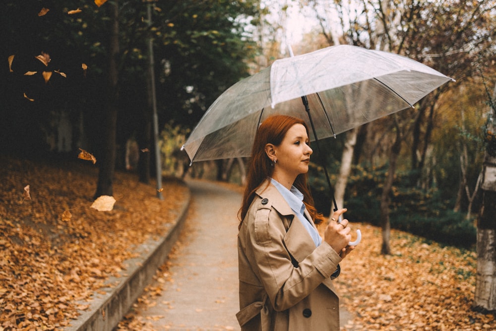 a woman in a trench coat holding an umbrella