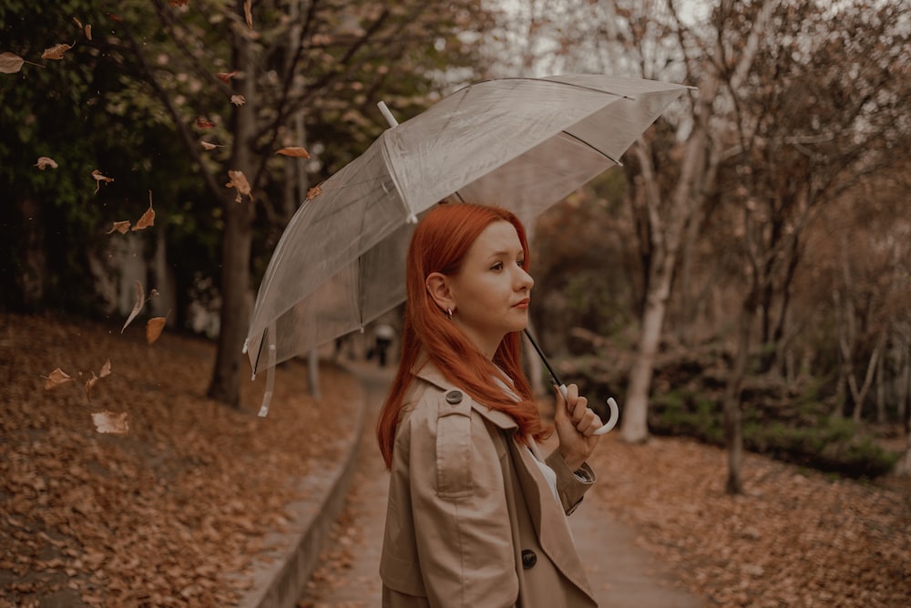 a woman with red hair is holding an umbrella