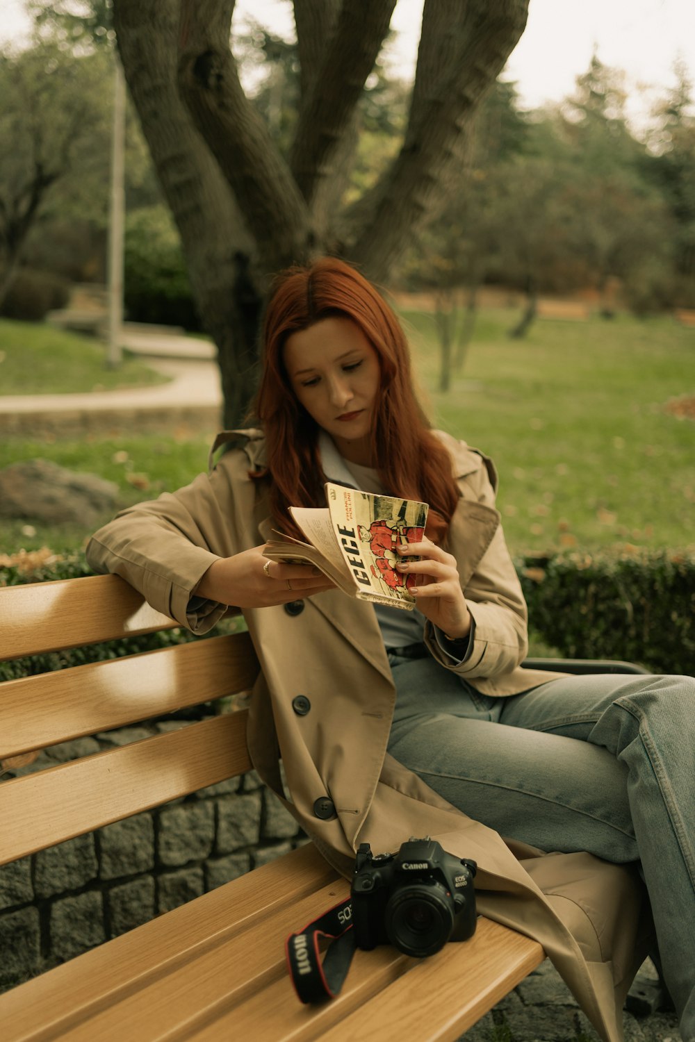 a woman sitting on a bench reading a magazine