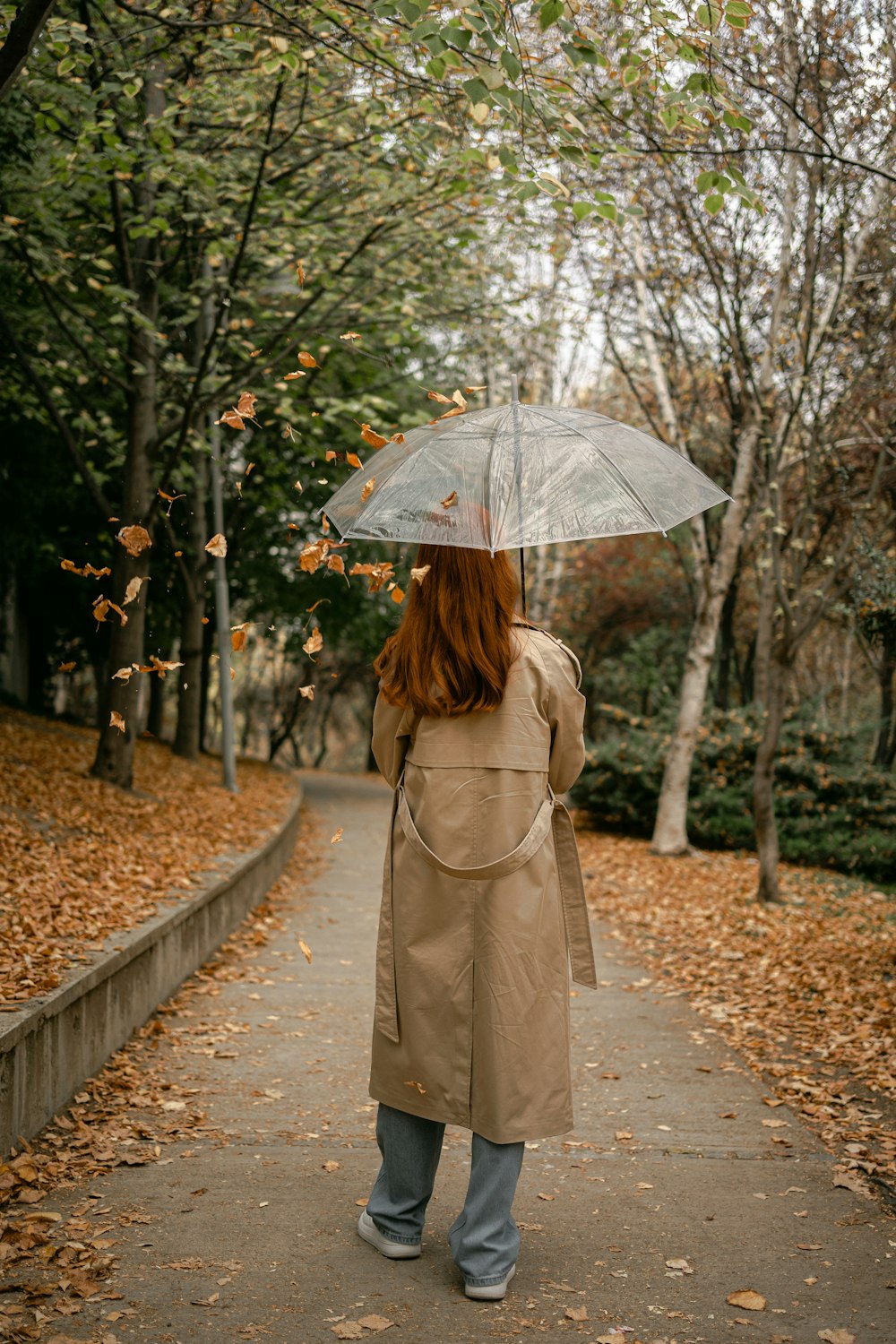 a woman walking down a path holding an umbrella