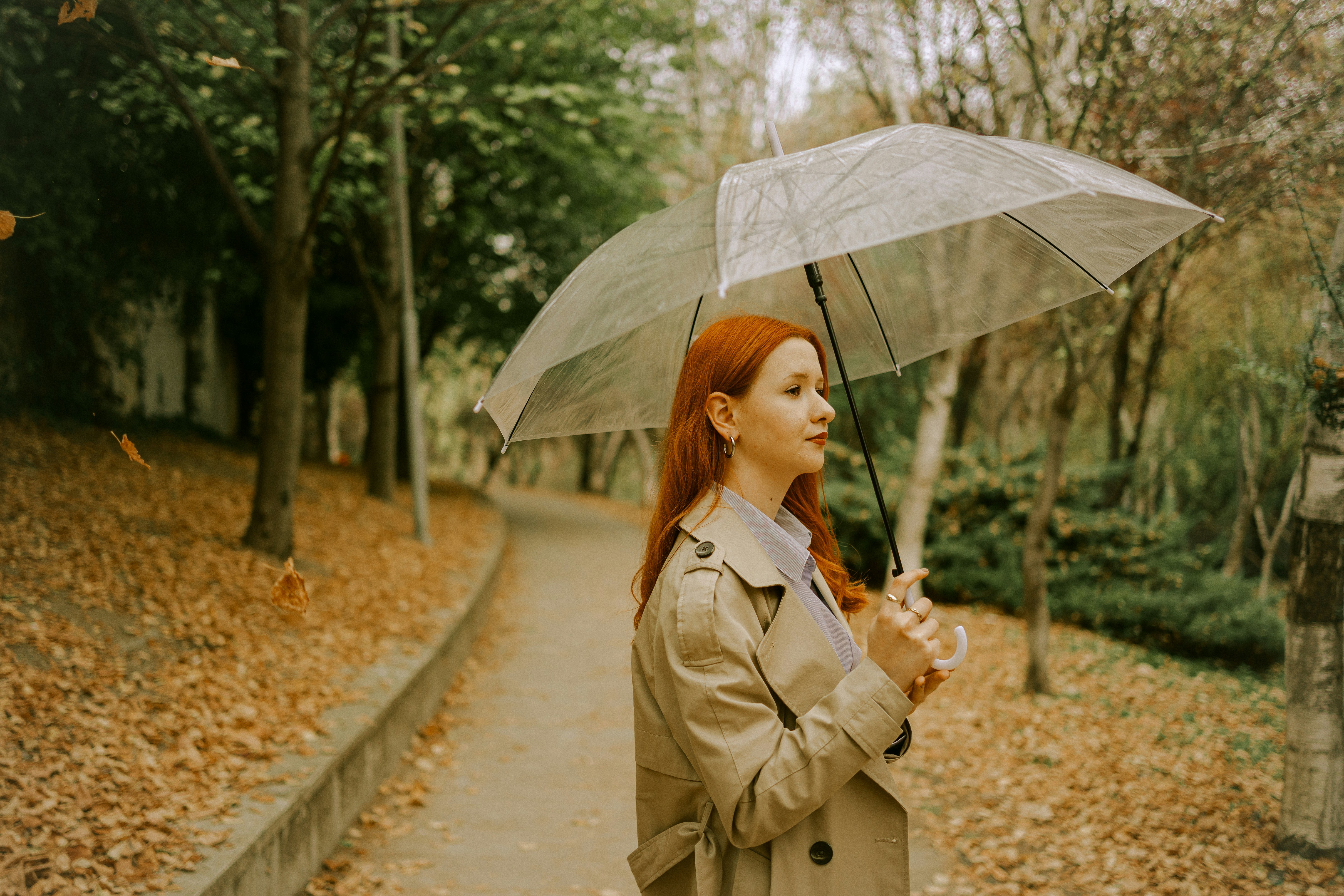 a woman in a trench coat holding an umbrella