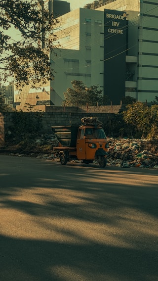 A bright orange taxi parked beside a bustling street in Ankleshwar, ready for a new journey.