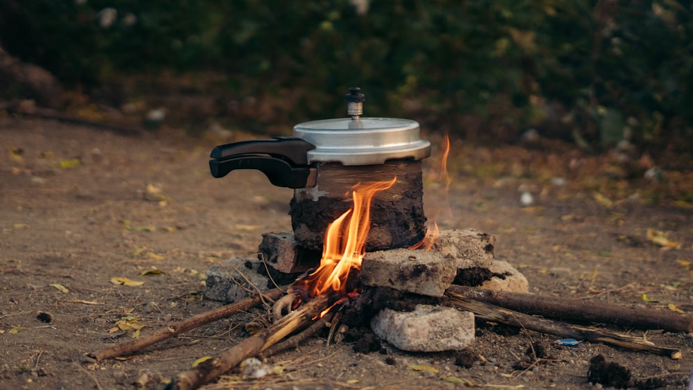 a campfire with a coffee pot on top of it