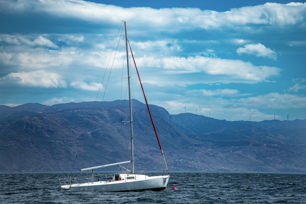 a sailboat in the water with mountains in the background