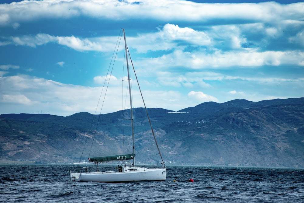 a sailboat in the water with mountains in the background
