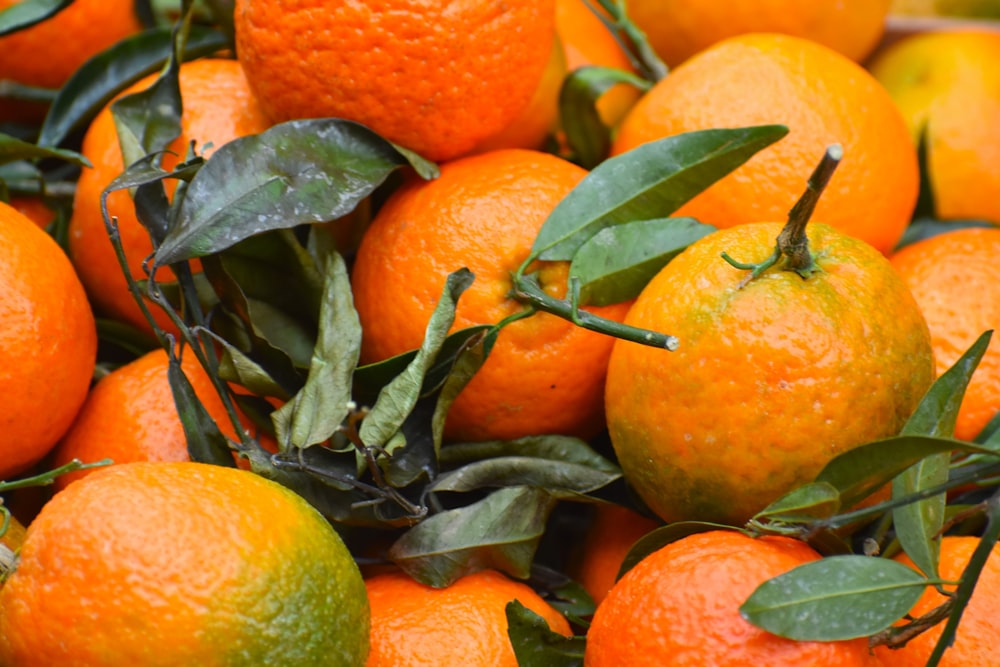a pile of oranges with leaves on them