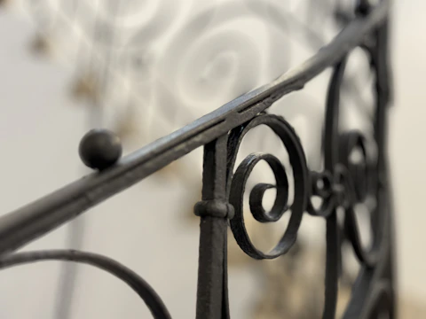 Close-up of a blacksmith’s decorative iron railing featuring hammered textures and graceful curves.