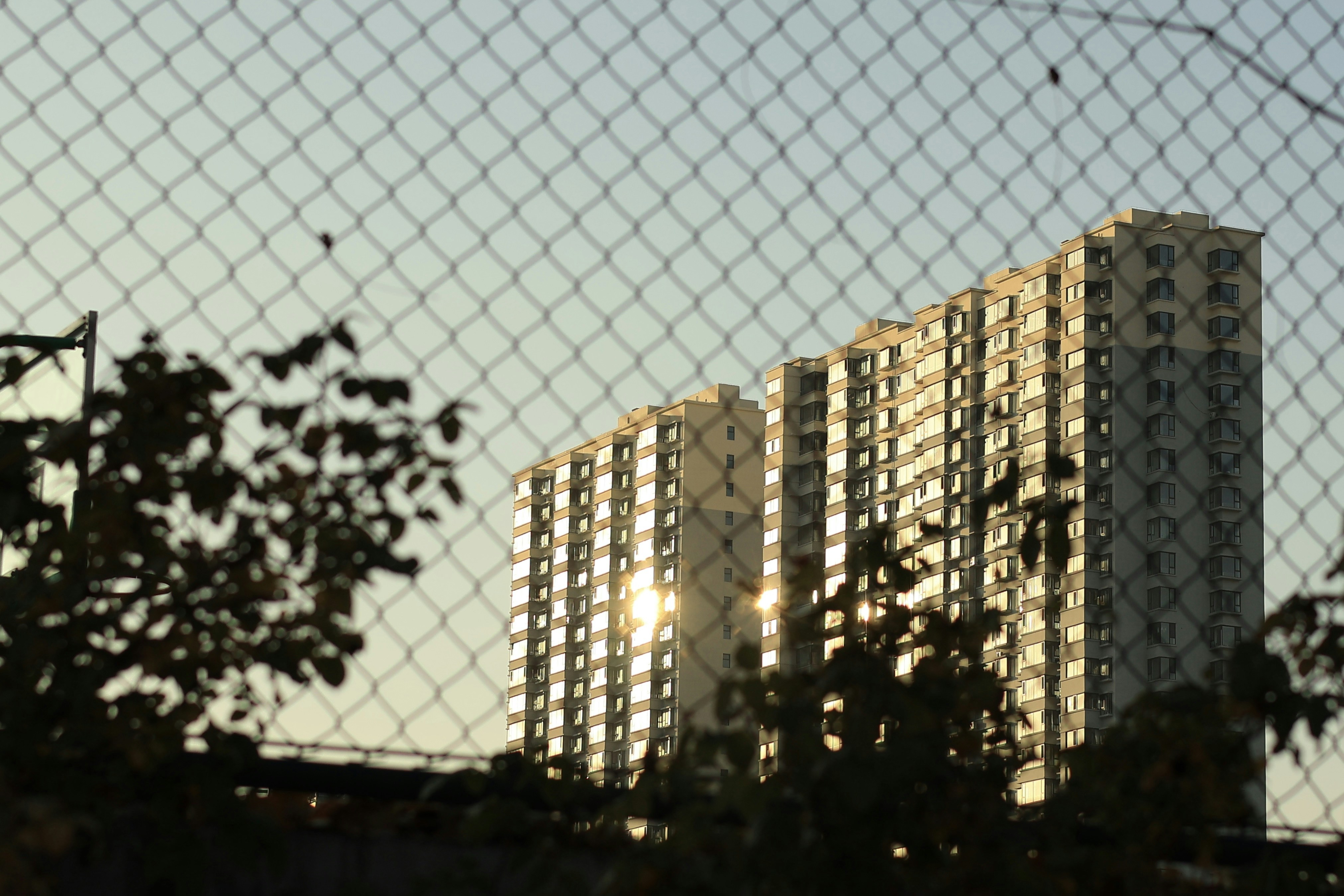 a view of a building through a chain link fence