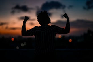 a silhouette of a man raising his arms in the air