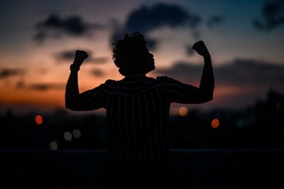 a silhouette of a man raising his arms in the air