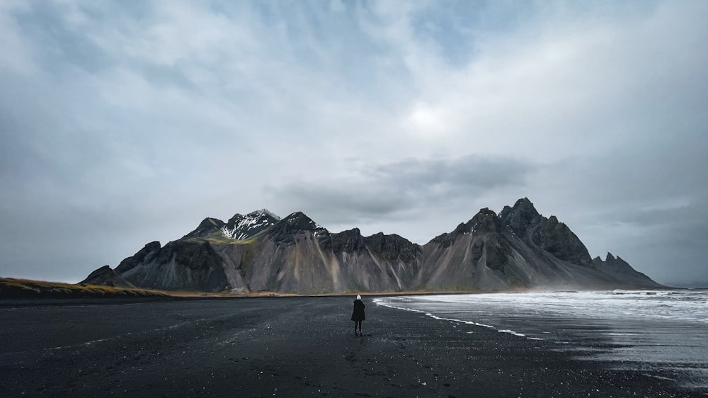 a person standing on a beach with mountains in the background