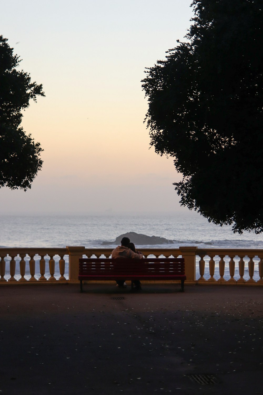 a person sitting on a bench near the ocean