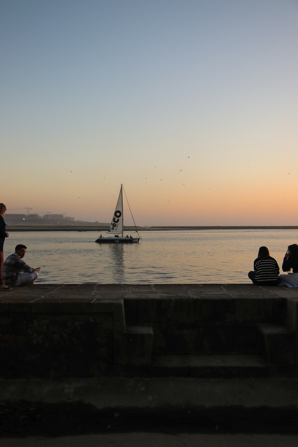 a group of people sitting next to a body of water
