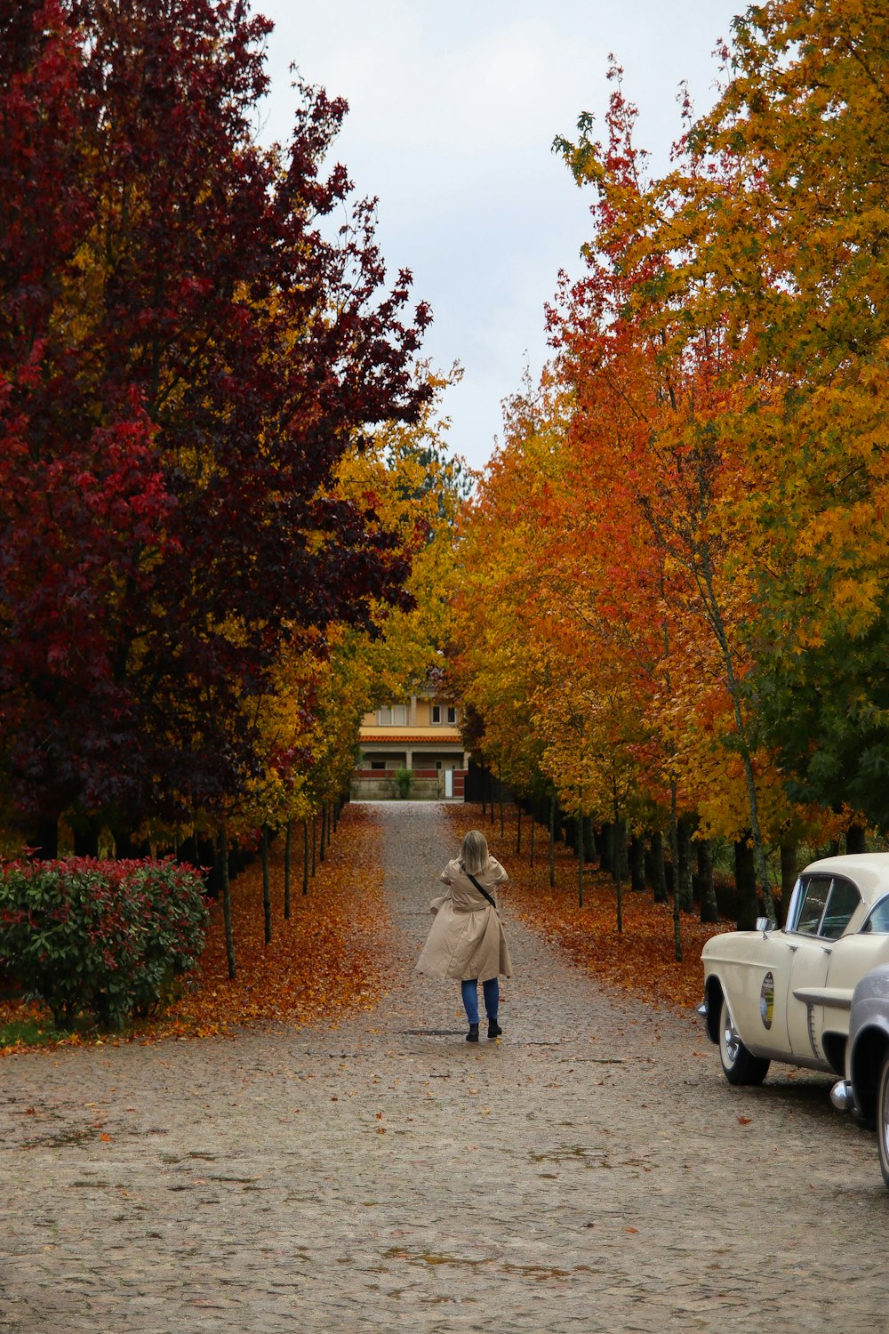 a woman walking down a dirt road next to a white truck