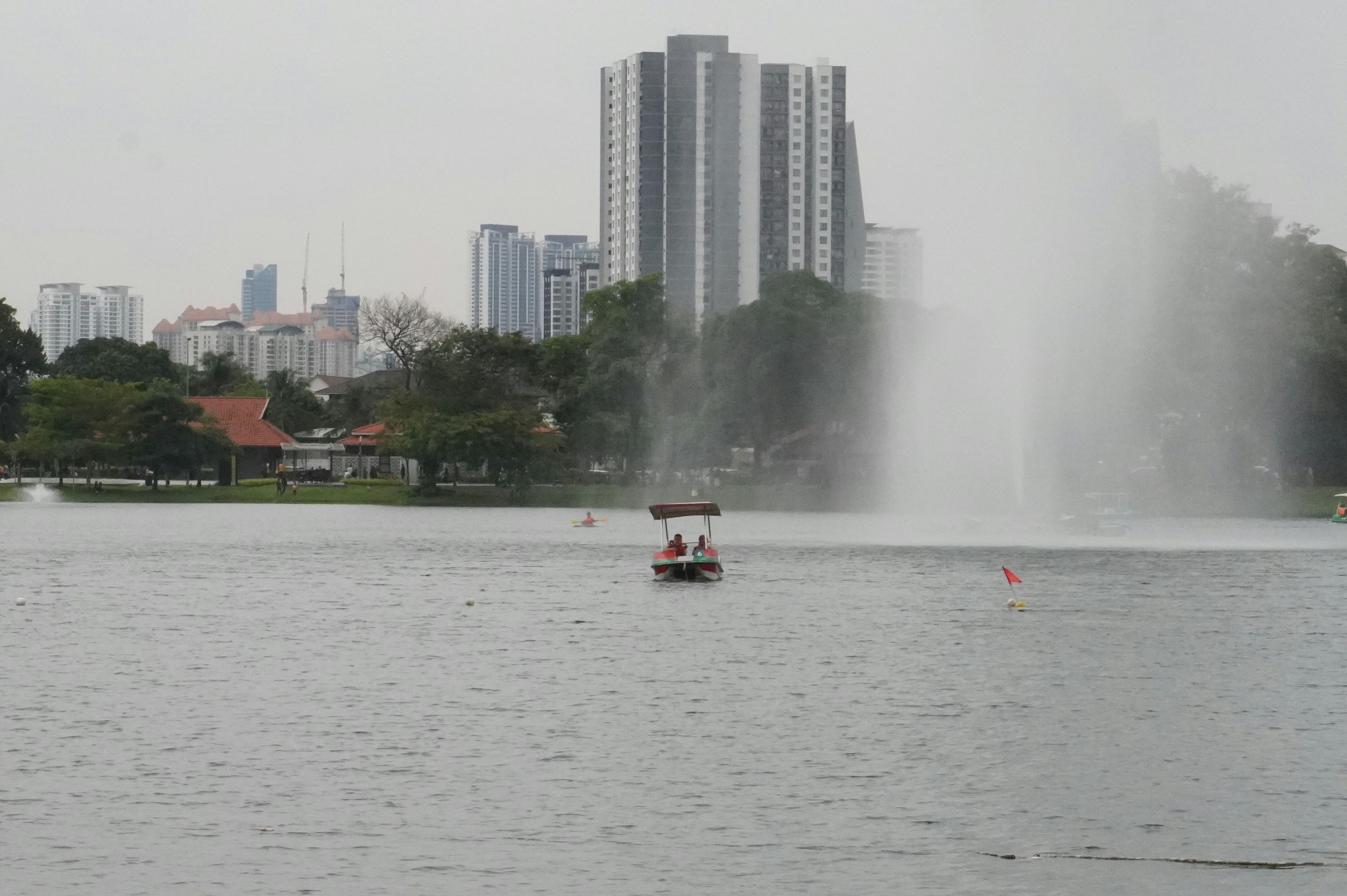 a boat in a lake with a fountain in the background