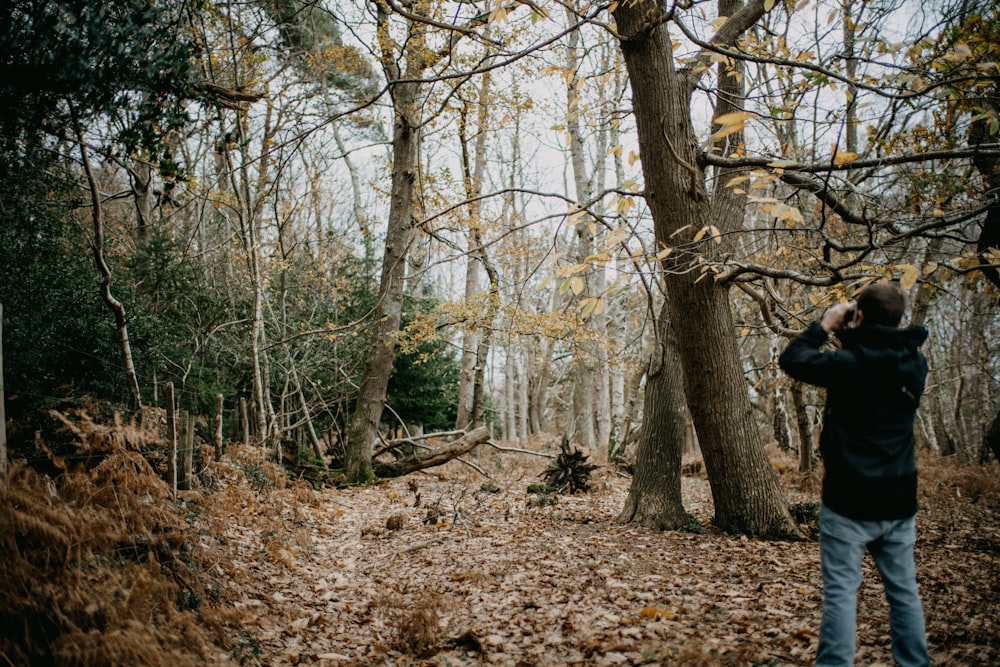 a man standing in the woods taking a picture