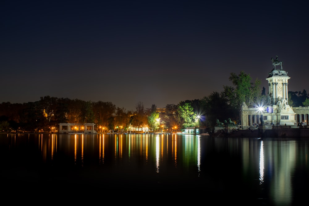 a clock tower sitting on top of a lake at night