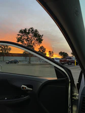Sunset view from a van parked on a mountain road with open doors.
