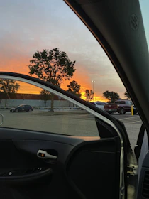 Sunset view from a van parked on a mountain road with open doors.