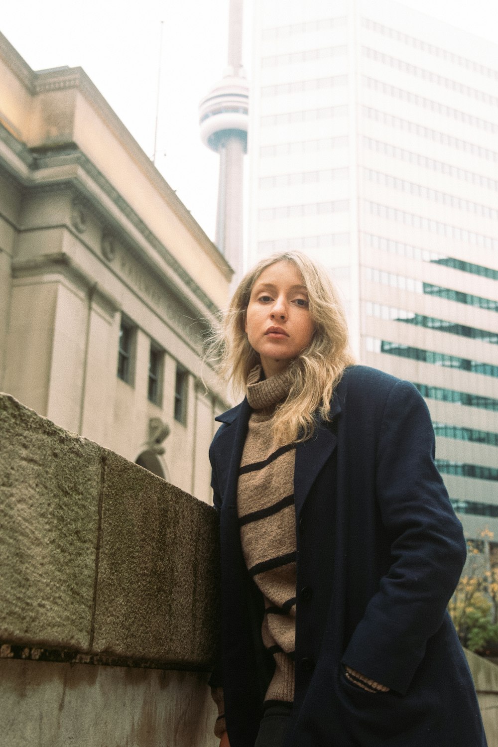 a woman leaning against a wall in front of a tall building