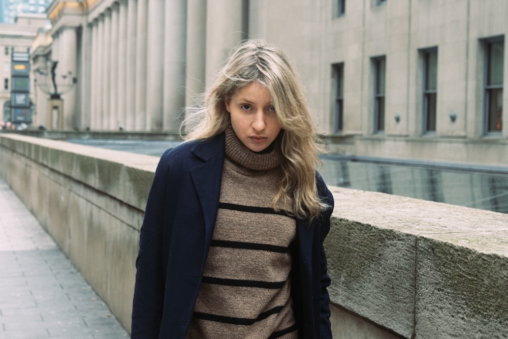 a woman standing on a sidewalk next to a building