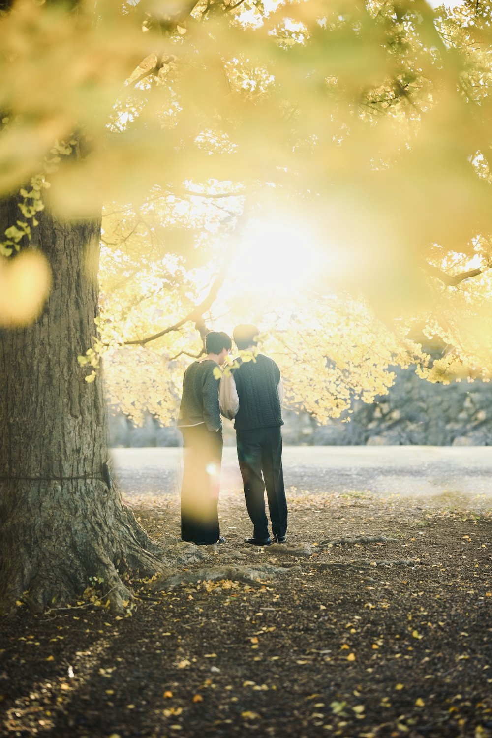 two people standing next to each other under a tree