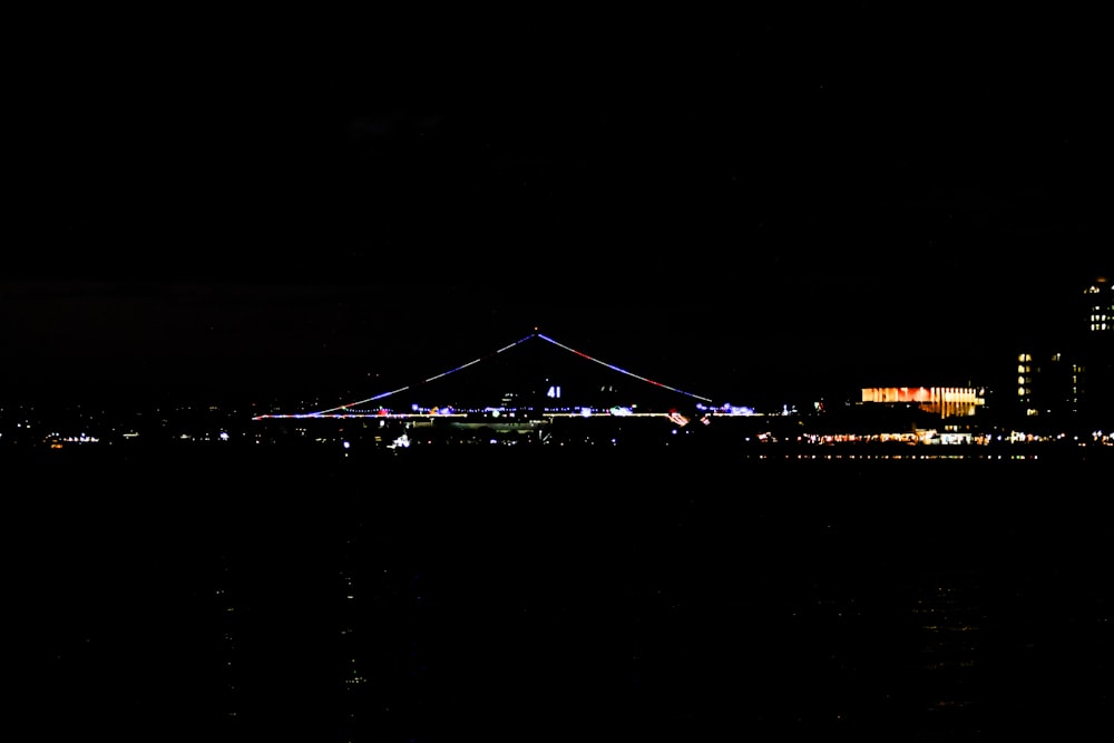 a city skyline at night with a bridge in the foreground