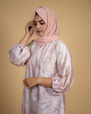 A soft blush pink hijab elegantly draped over a mannequin in a minimalist setting.