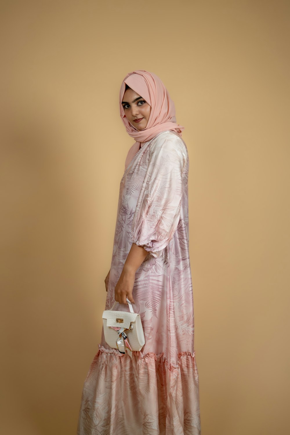 a woman in a pink dress holding a white purse