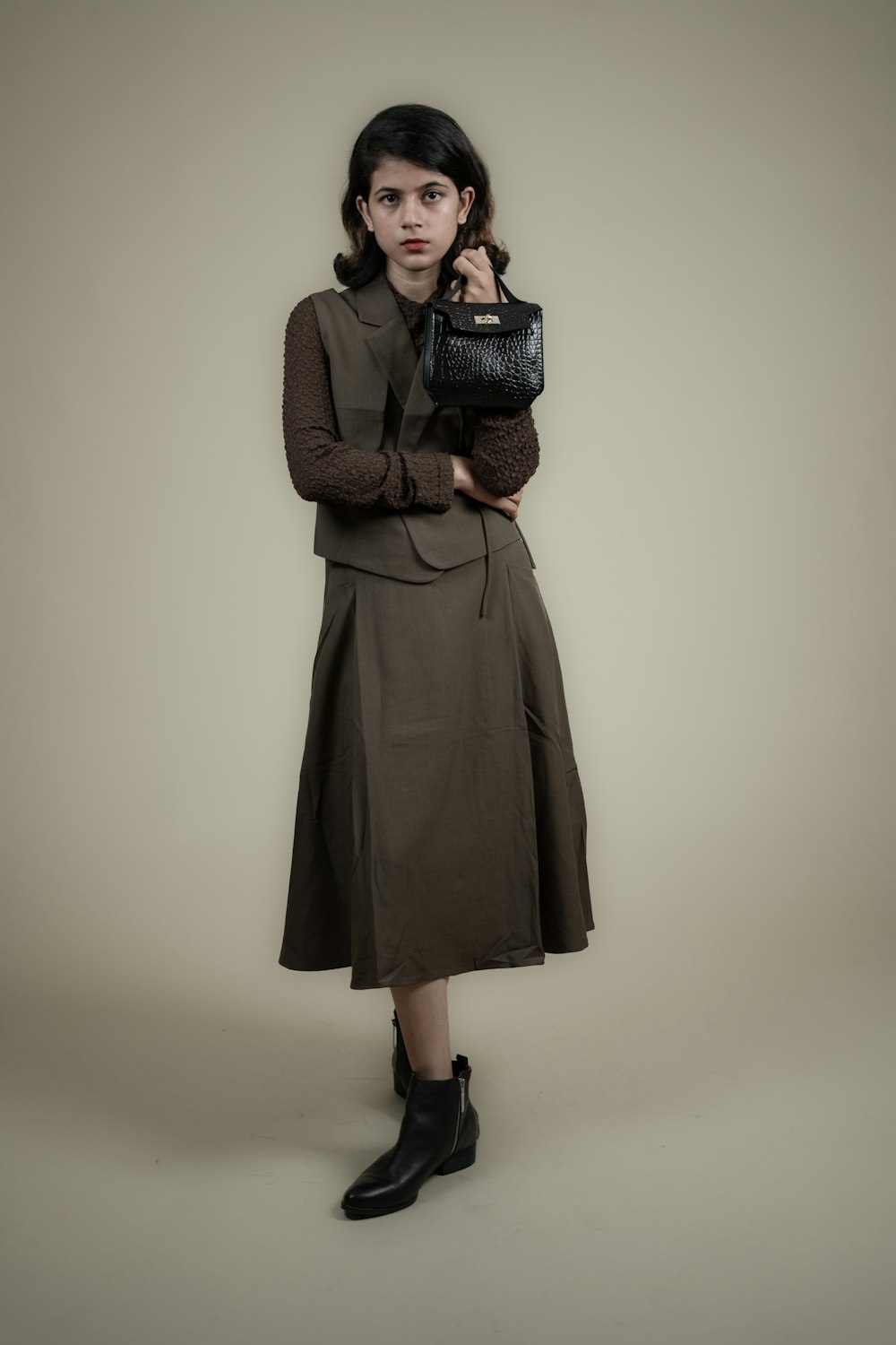 a woman in a brown dress holding a black purse