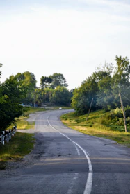 A rural road winding through green fields under a clear sky.