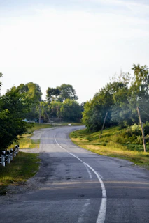 A freshly paved government road winding through a rural area in West Bengal under clear skies