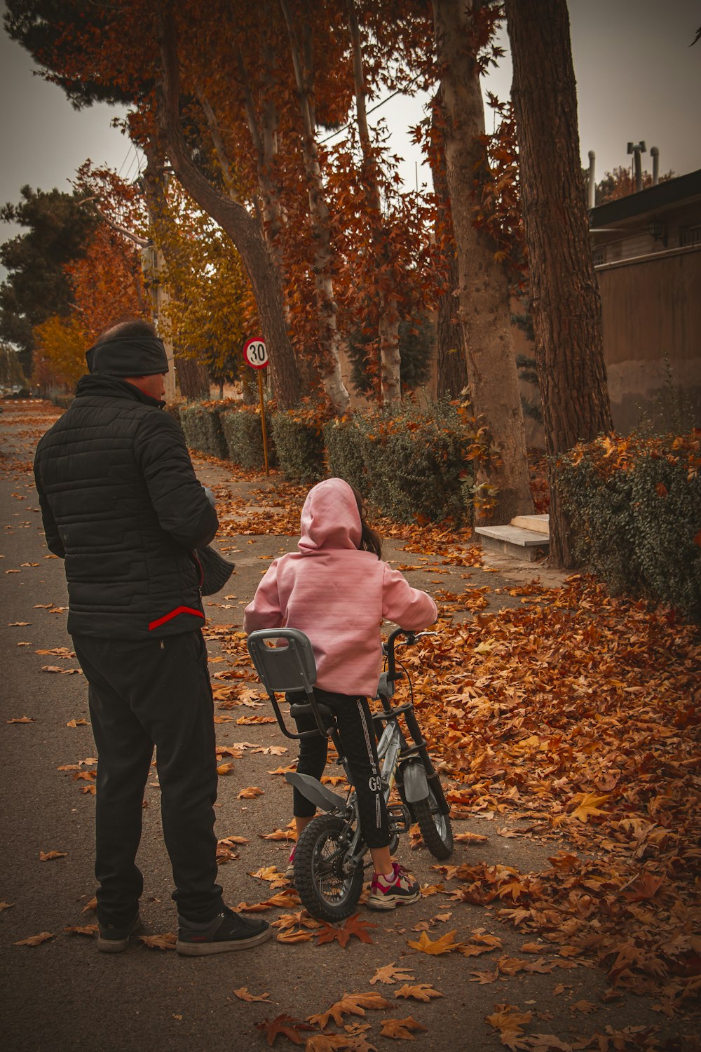 a man standing next to a child on a bike