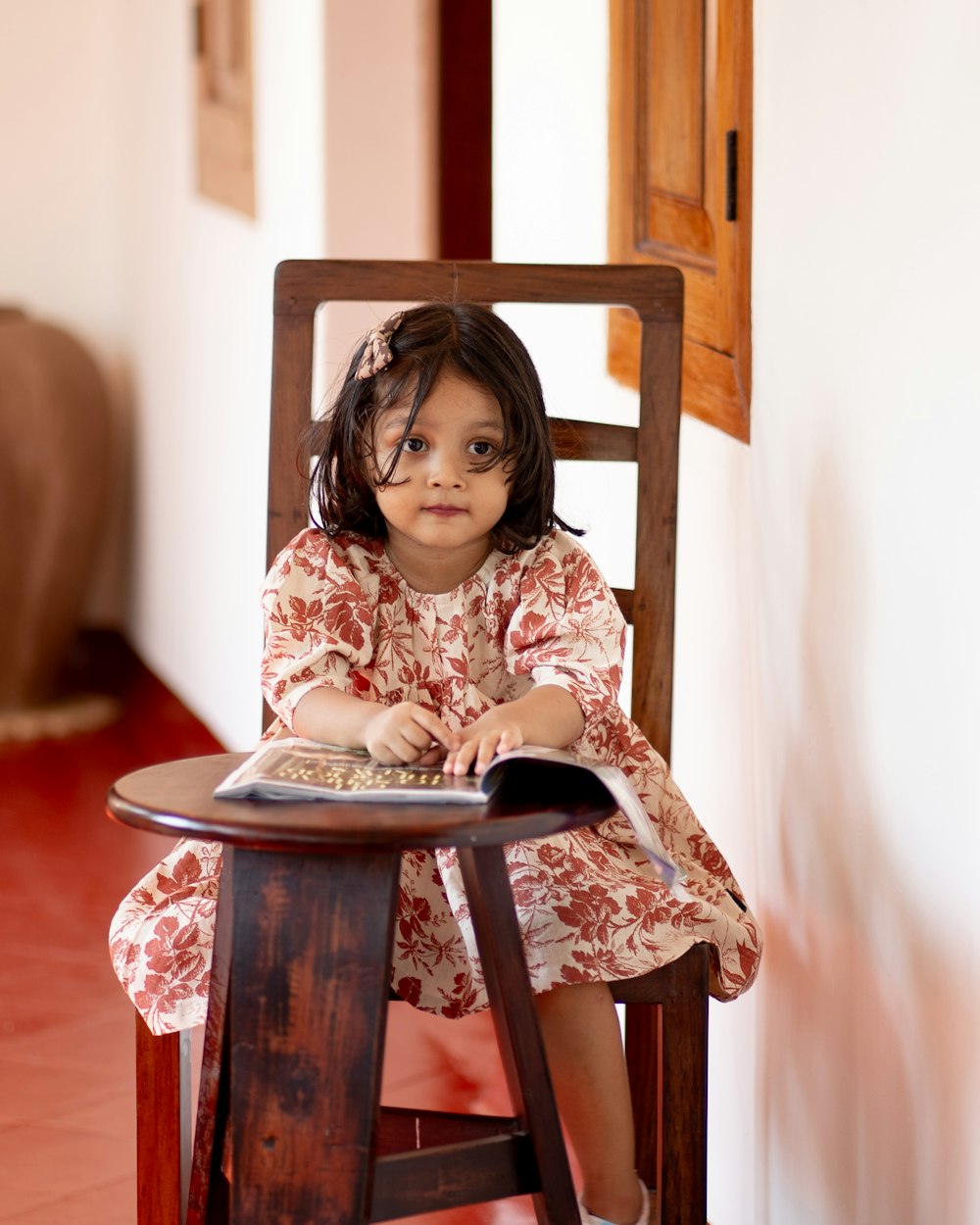 a little girl sitting in a wooden chair