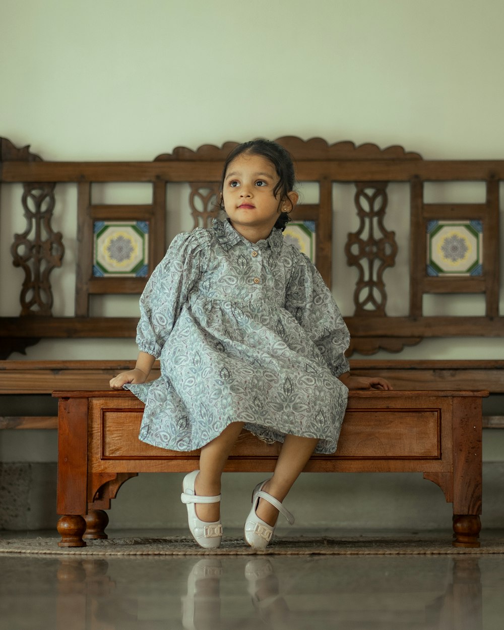 a little girl sitting on a wooden bench