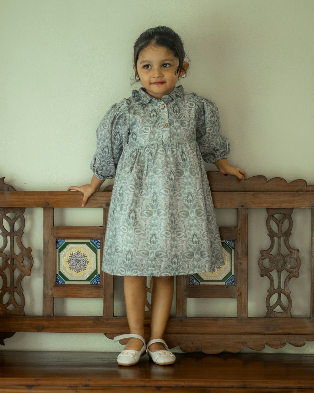 a little girl standing on a wooden bench