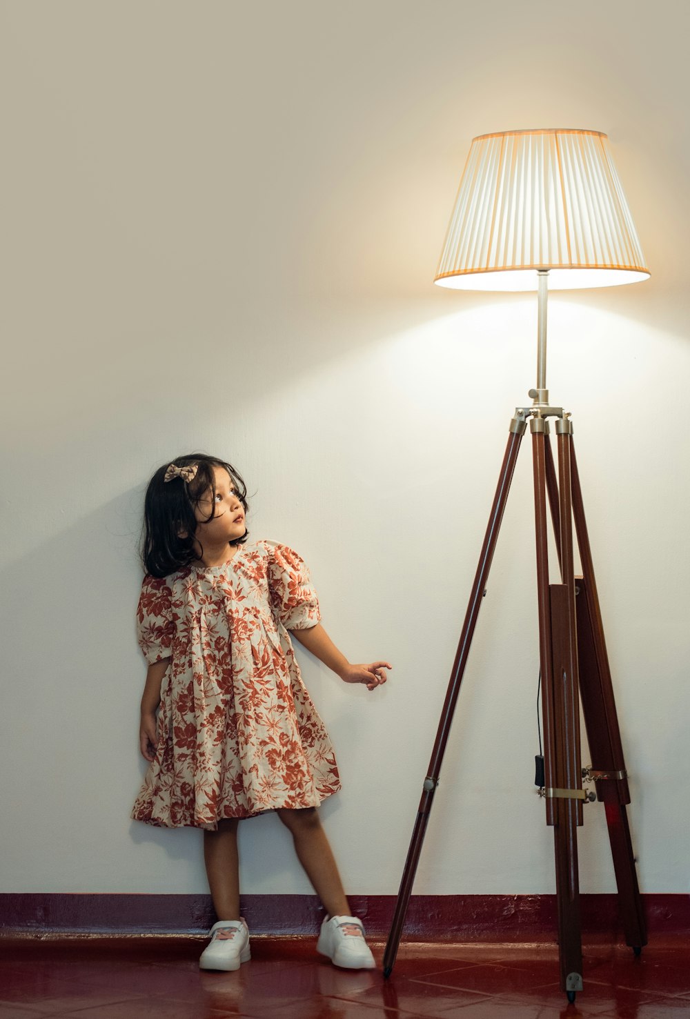 a little girl standing in front of a lamp