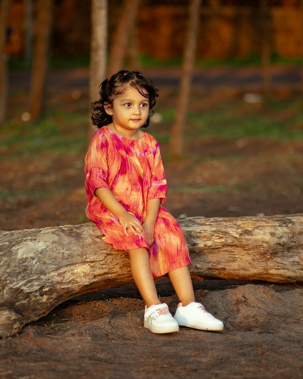 a little girl is sitting on a log