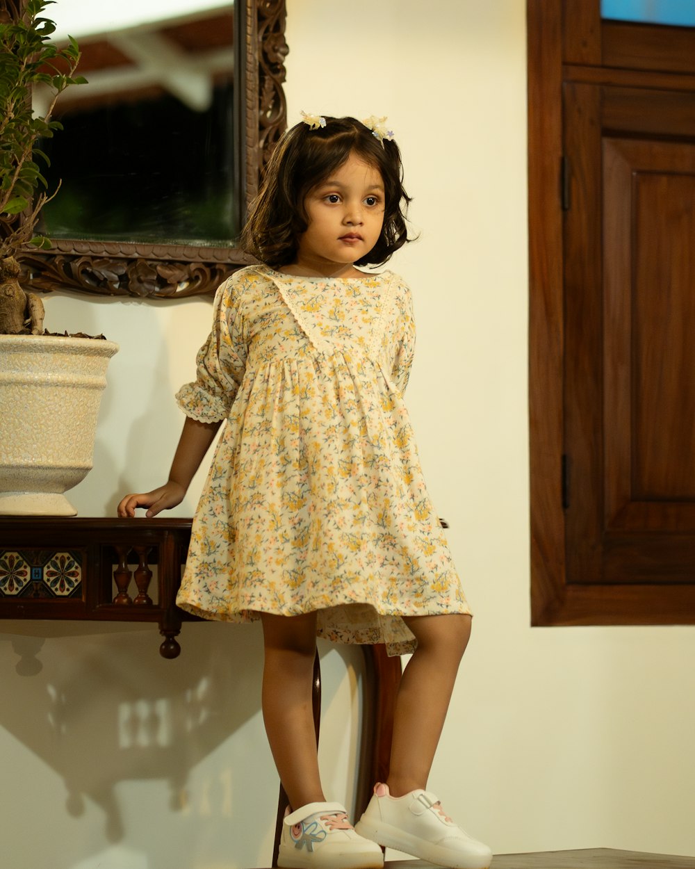a little girl standing on a chair in front of a mirror