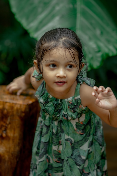a little girl standing next to a tree stump