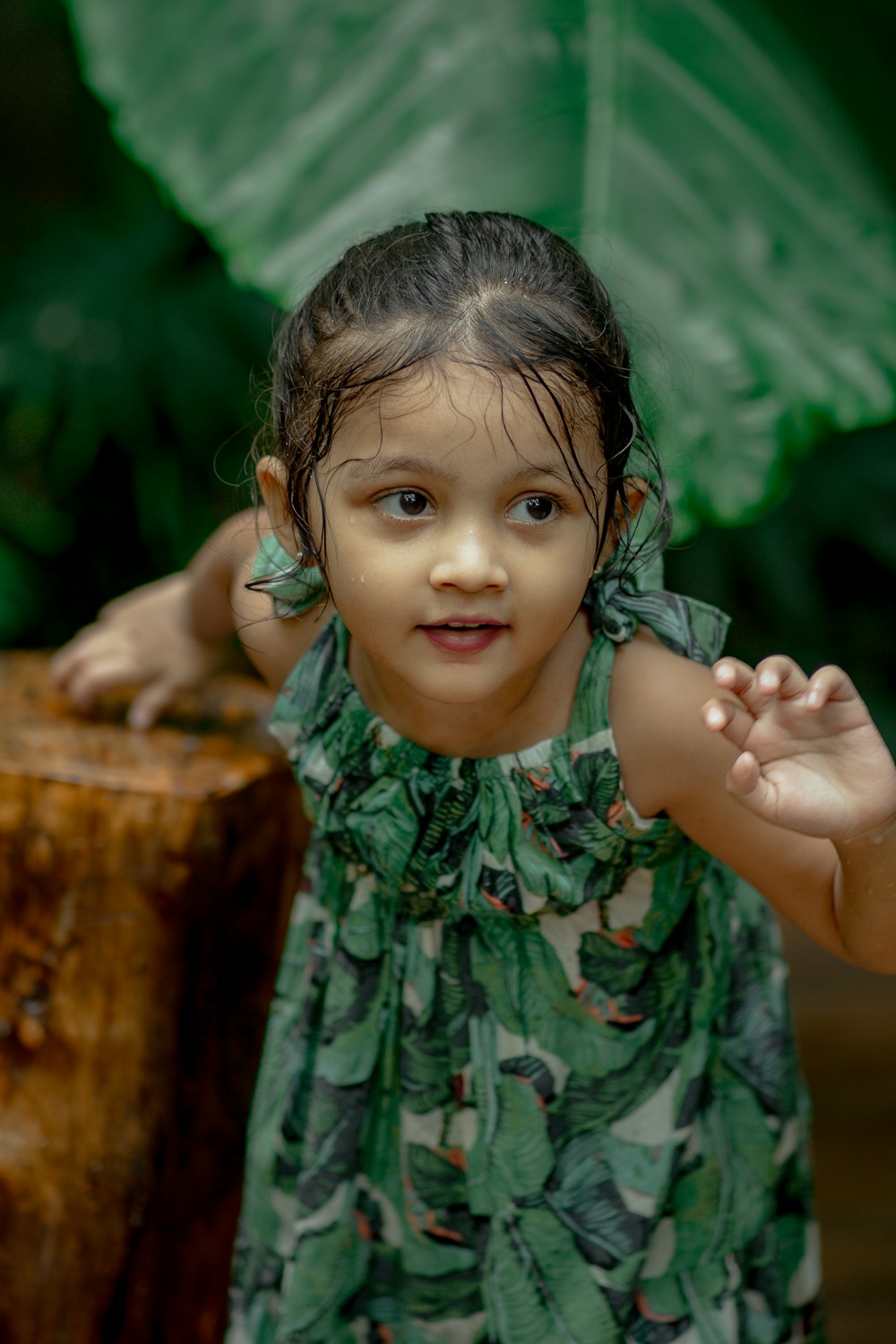 a little girl standing next to a tree stump